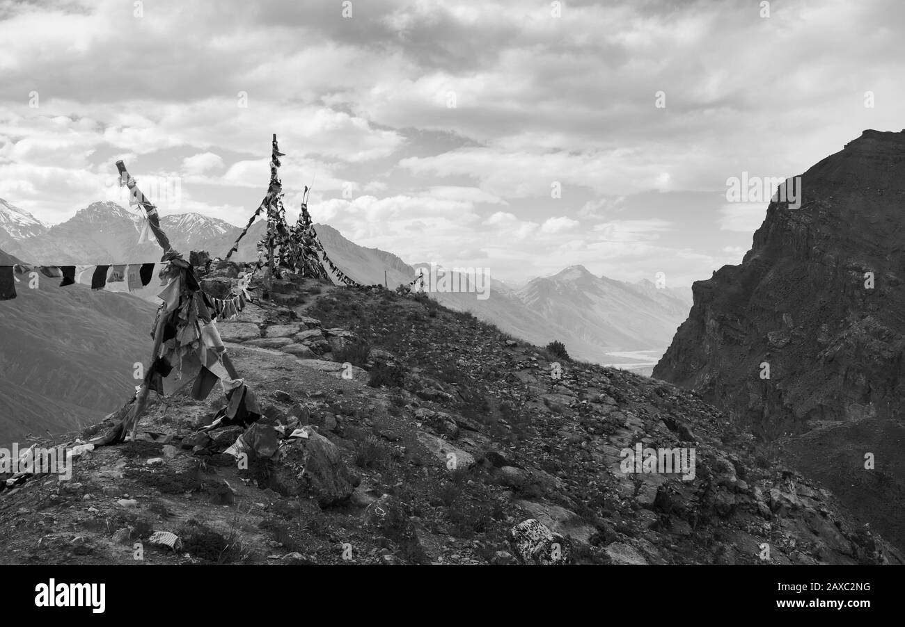 Uno scorcio del fiume e della valle di Spiti e delle vette dell'Himalaya e delle bandiere di preghiera in una giornata estiva travolsa vicino a Kaza, Himachal Pradesh, India. Foto Stock