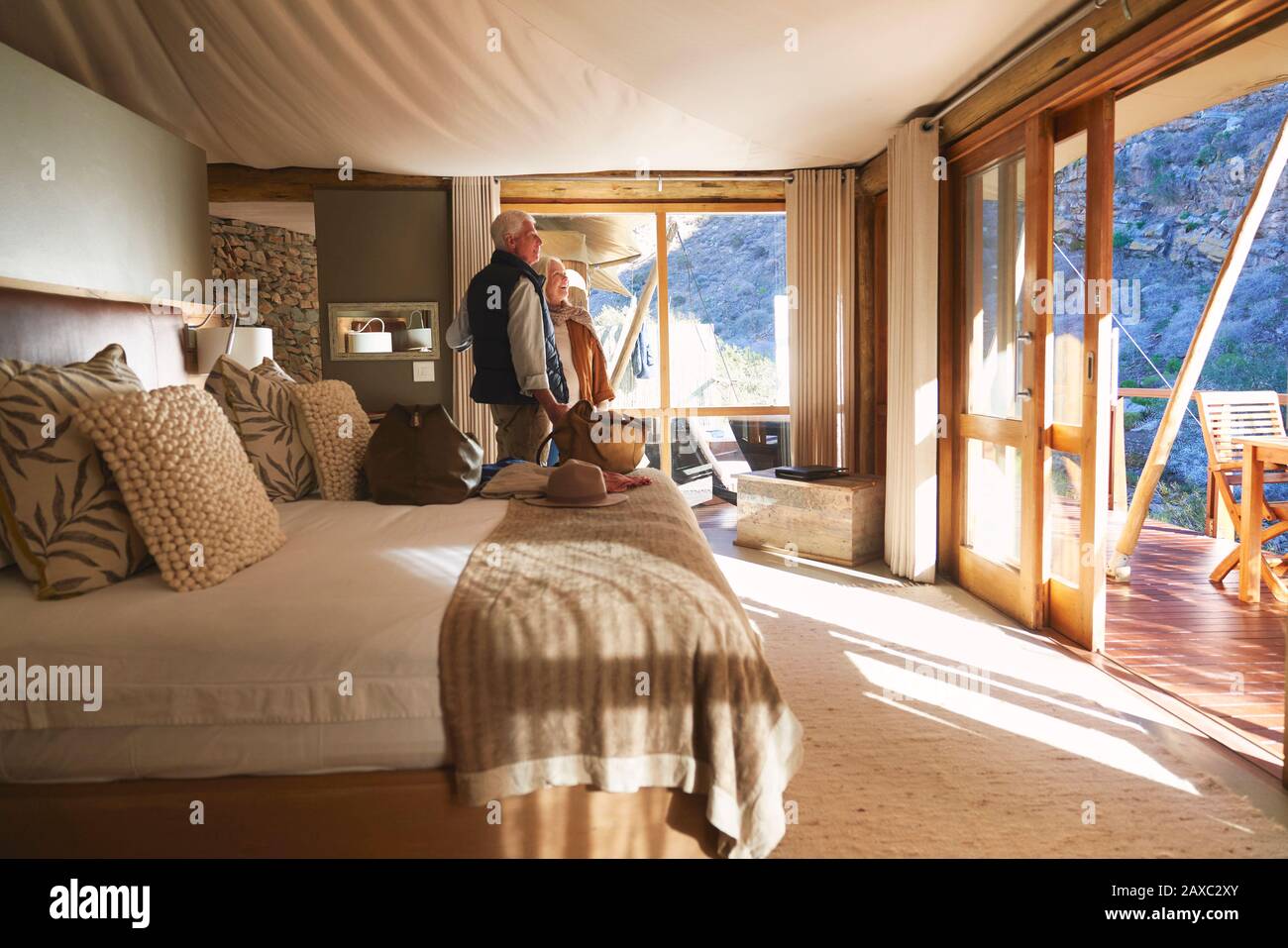Una coppia felice che arriva in una soleggiata camera d'albergo safari Lodge Foto Stock