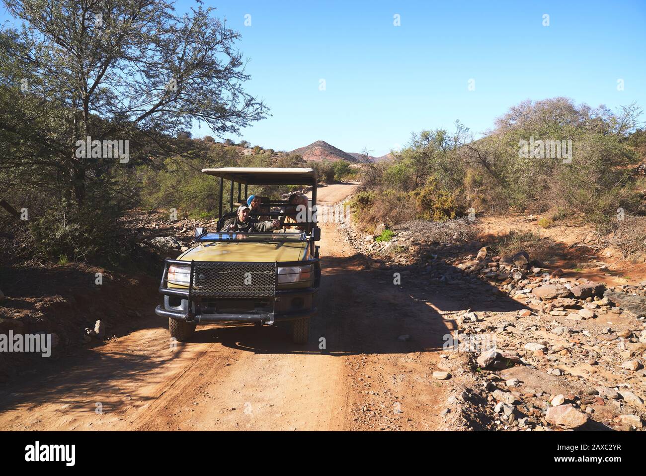 Tour Safari in gruppo a bordo di un veicolo fuoristrada sulla soleggiata strada sterrata Foto Stock