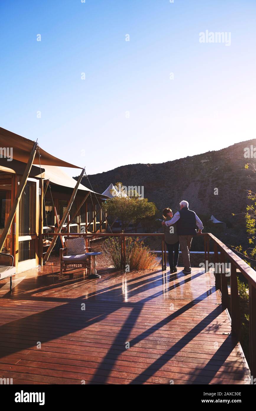 Affettuoso senior coppia abbracciando su soleggiato safari Lodge balcone Foto Stock