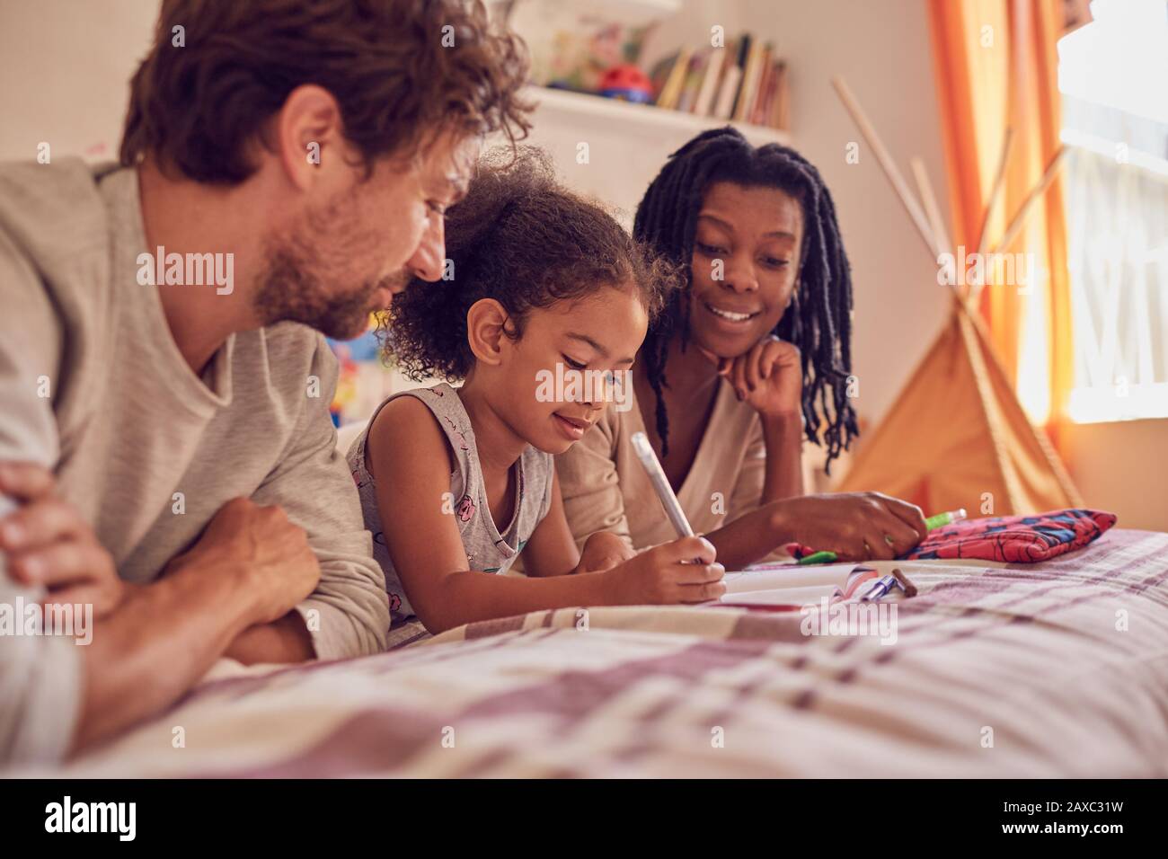 Giovane famiglia colorazione sul letto Foto Stock
