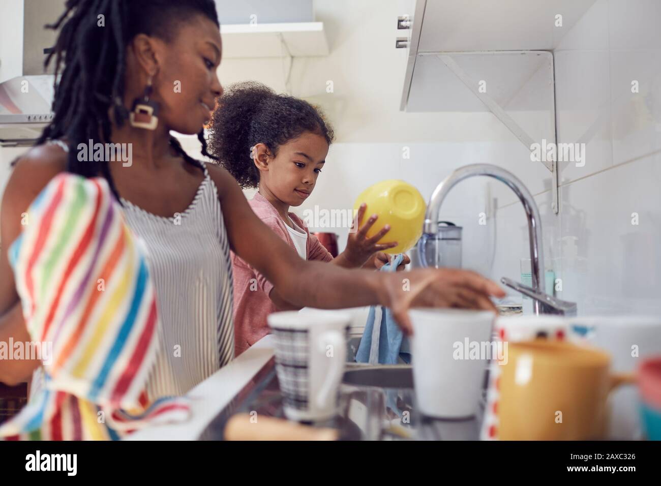 La madre e la figlia lavano i piatti al lavello della cucina Foto Stock