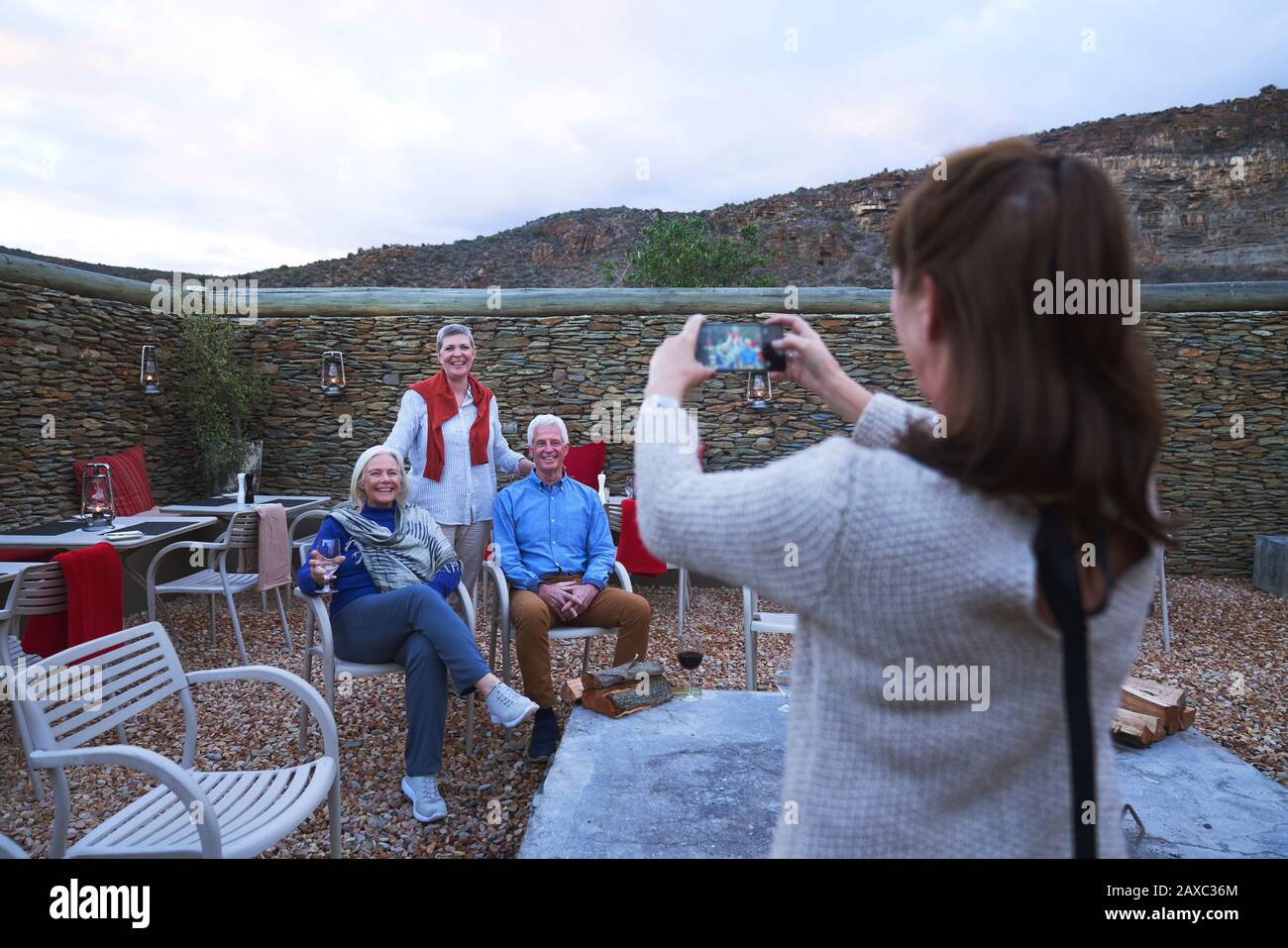 Donna con macchina fotografica telefono fotografare gli amici anziani sul patio Foto Stock
