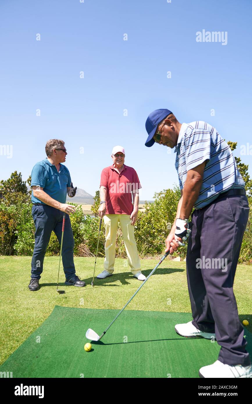 Golf maschio che pratica l'oscillazione al campo pratica di golf Foto Stock