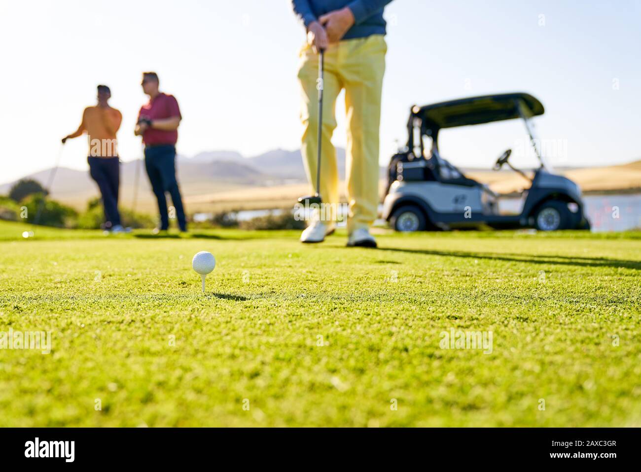 Maschio golfista che si prepara a tee off sul soleggiato campo da golf Foto Stock