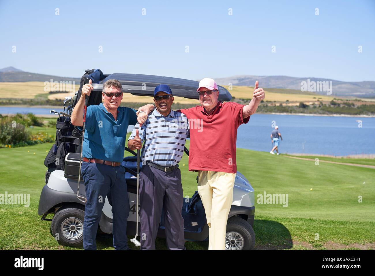 Ritratto felice maturo golfisti maschi a golf cart su campo soleggiato Foto Stock