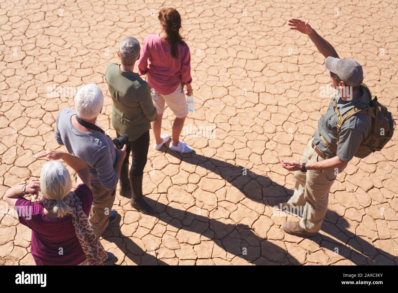 Guida turistica di Safari che parla con il gruppo su una terra piena di sole crepe Foto Stock