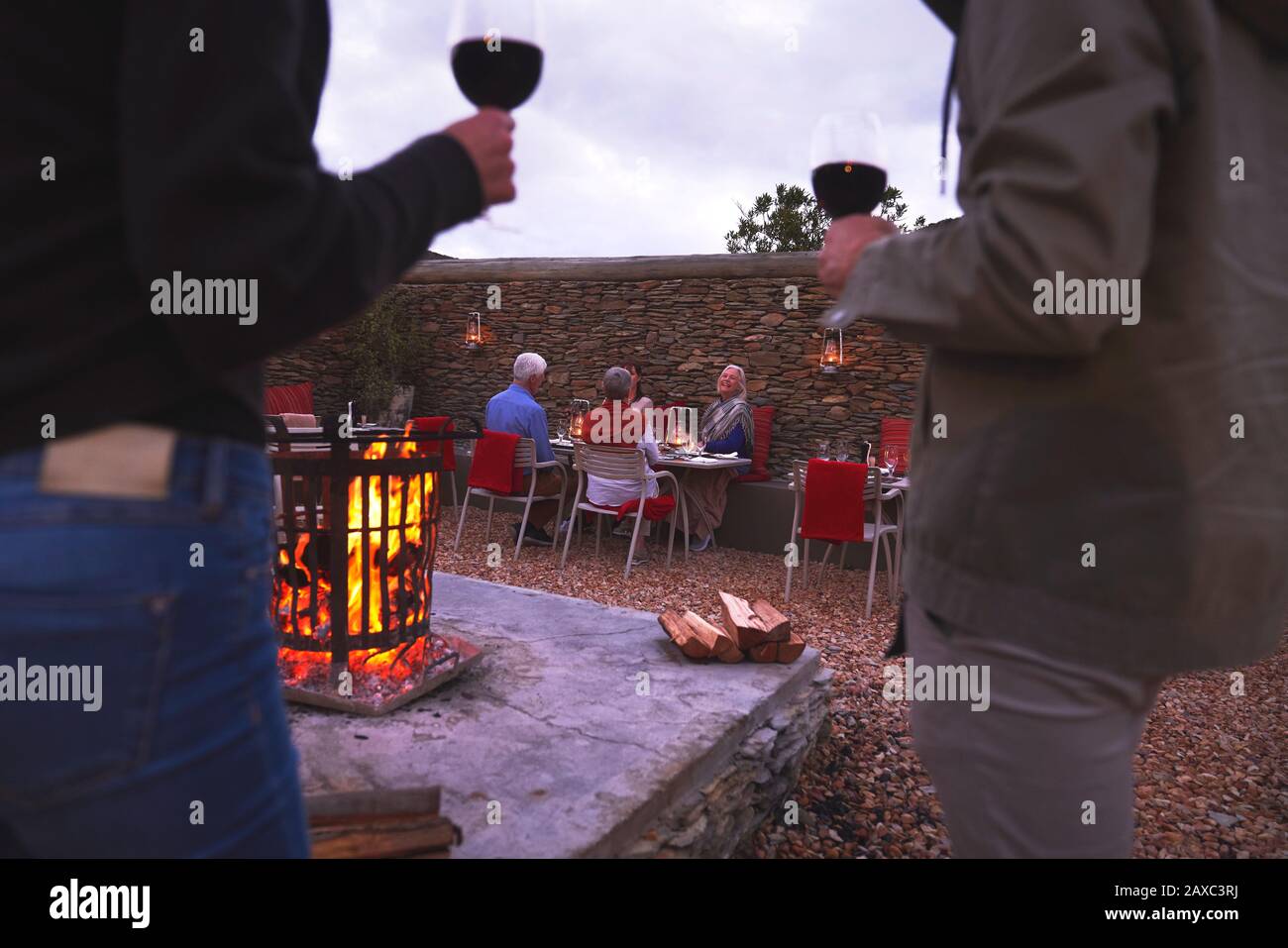 Coppia e amici anziani mangiare bere vino sul patio con camino Foto Stock