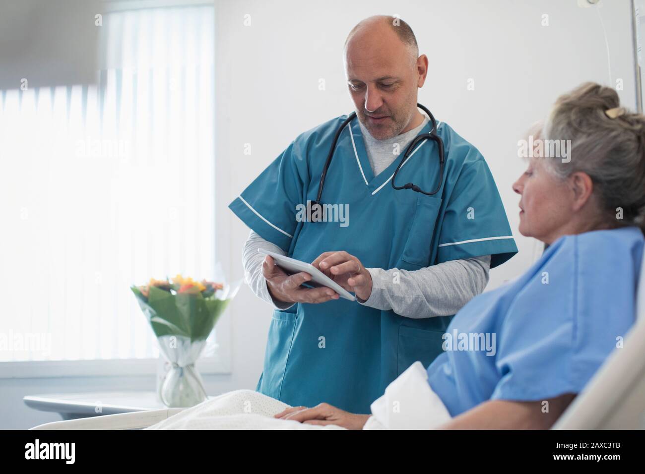 Dottore con tablet digitali che fa giri, parlando con pazienti anziani nel letto ospedaliero Foto Stock