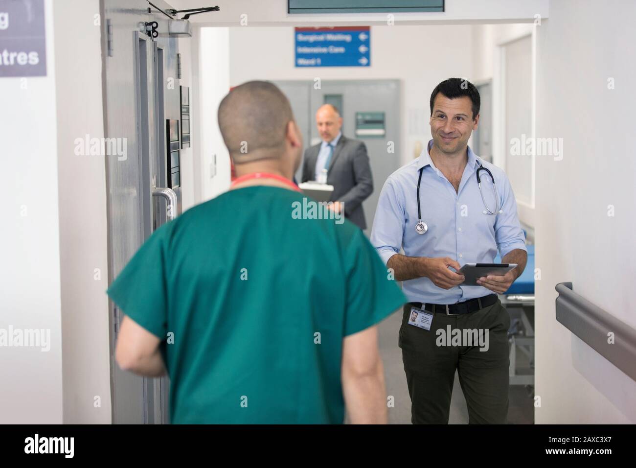 I medici di sesso maschile salutano, passando l'un l'altro nel corridoio dell'ospedale Foto Stock