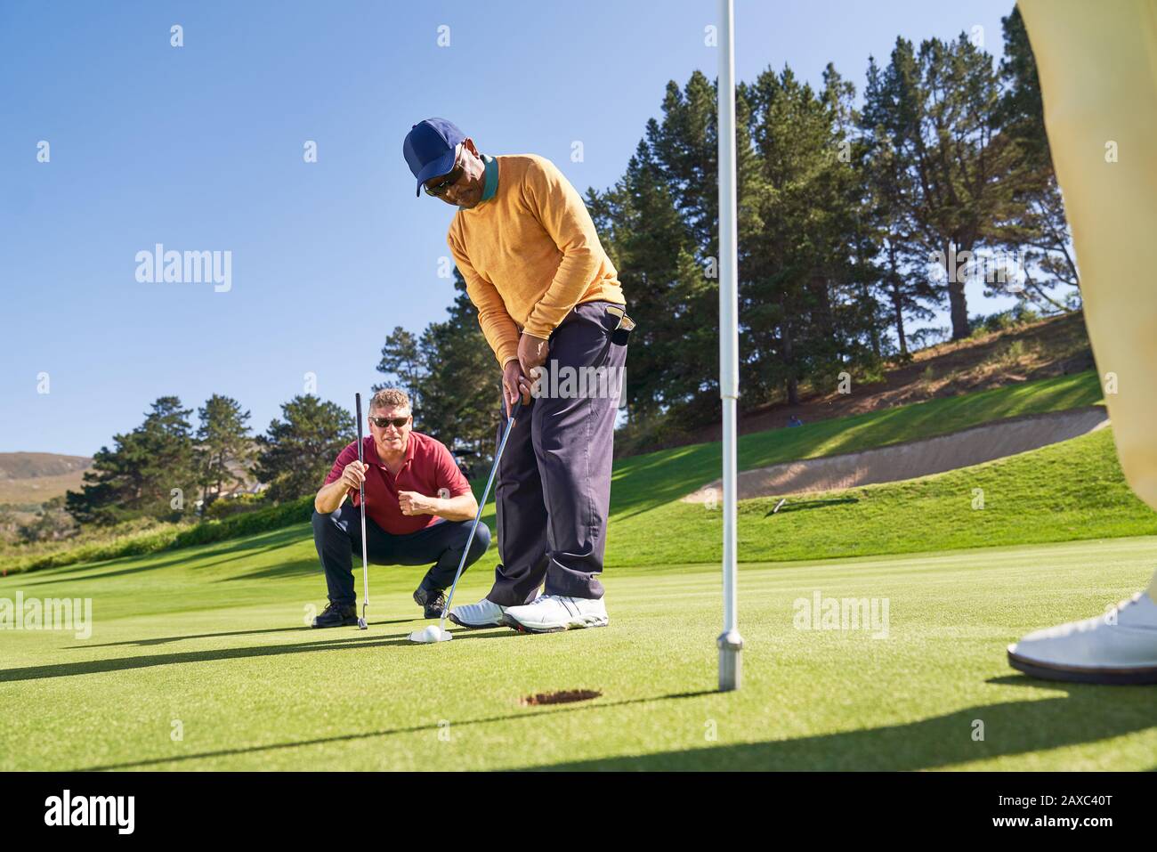 Maschio golfista mettere in buca sul soleggiato campo da golf putting green Foto Stock