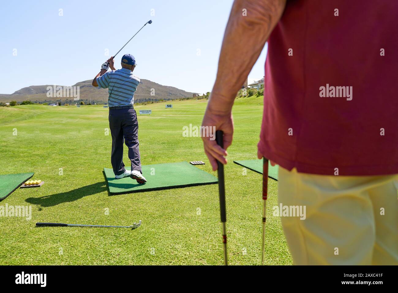 Golfista maschile che pratica al sole campo da golf driving range Foto Stock