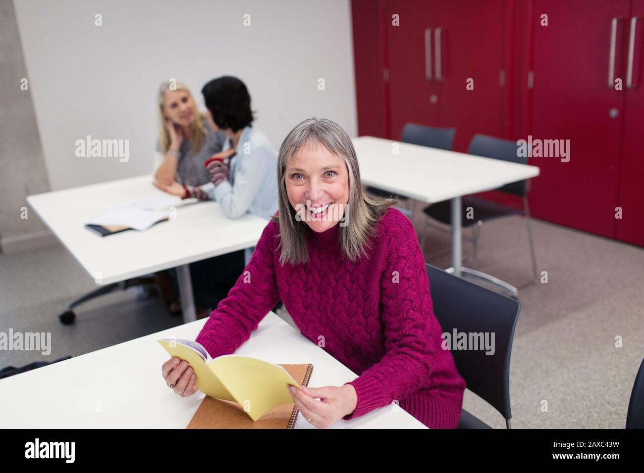 Ritratto sorridente, sicuro studente universitario di comunità femminile lettura in classe Foto Stock