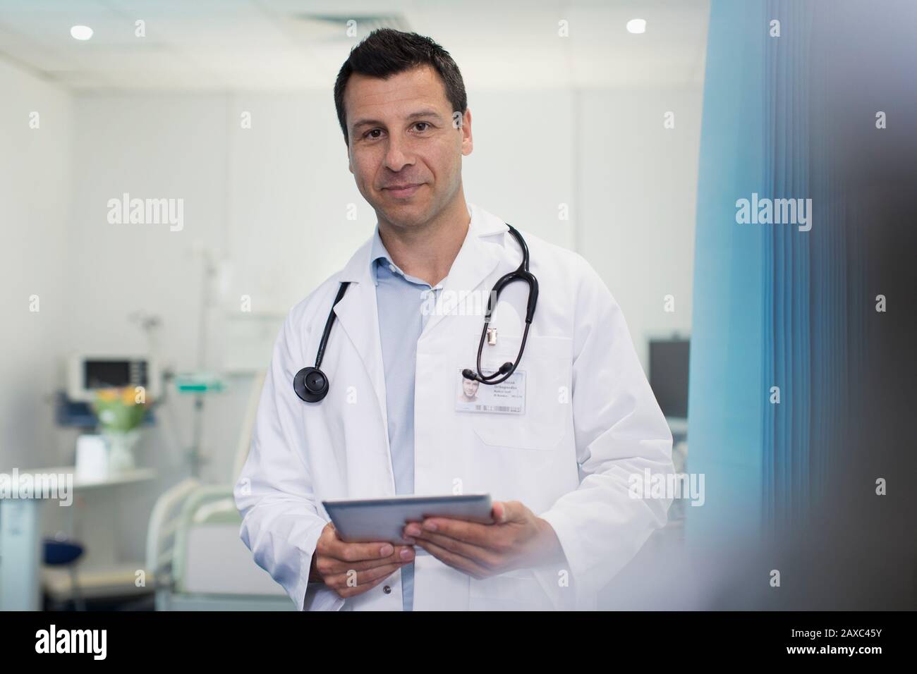 Medico maschile con ritratto sicuro che usa un tablet digitale nella stanza dell'ospedale Foto Stock
