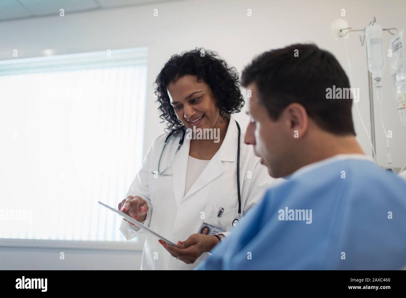 Medico con tablet digitali che si arrotonda, parlando con il paziente nella stanza dell'ospedale Foto Stock