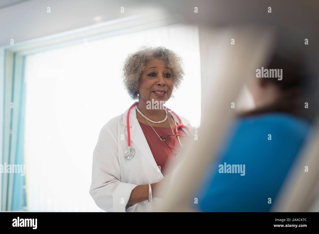 Donne senior medico che fanno giri, parlando con il paziente nella stanza dell'ospedale Foto Stock