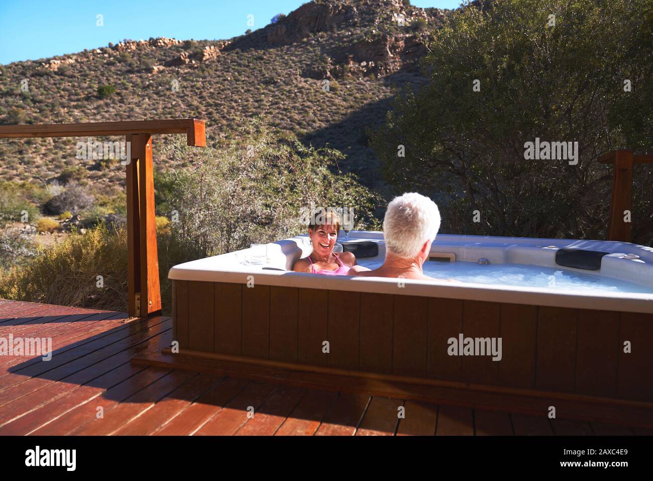 Felice coppia senior rilassante in vasca idromassaggio sul soleggiato balcone safari Foto Stock