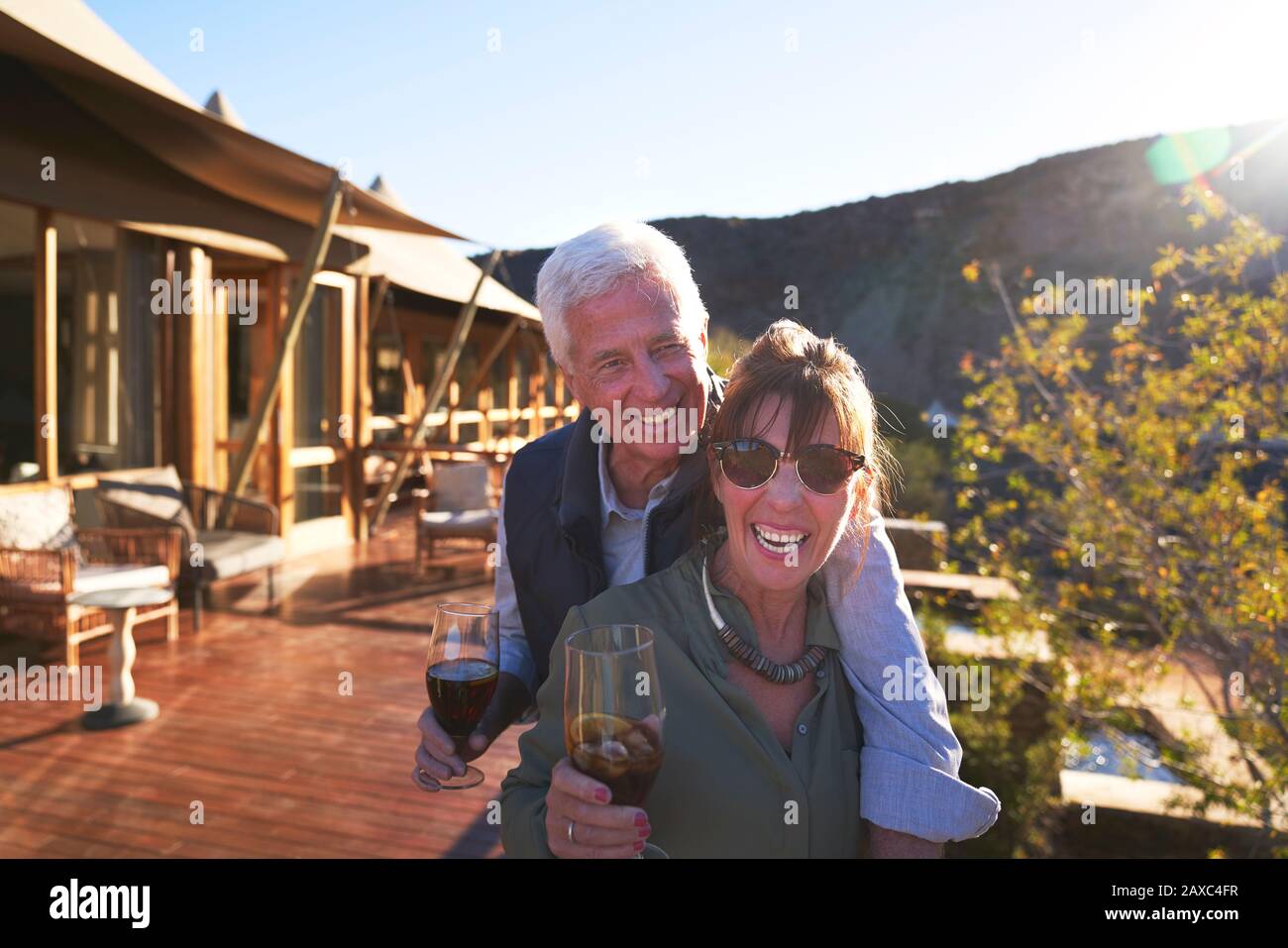 Ritratto felice coppia senior bere tè freddo sul balcone soleggiato hotel Foto Stock