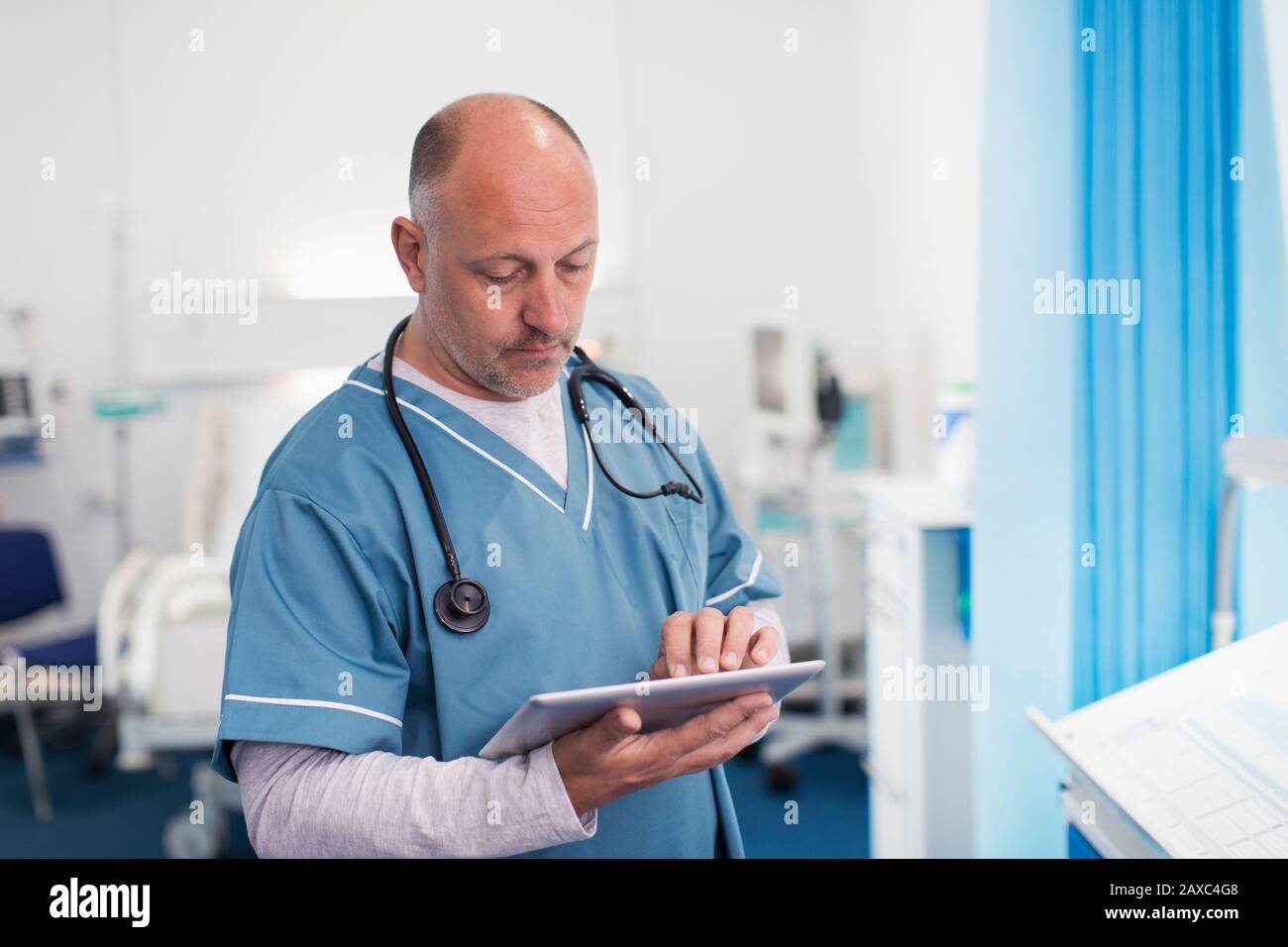 Medico di sesso maschile che utilizza un tablet digitale nella sala ospedaliera Foto Stock