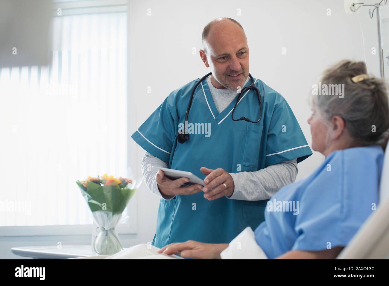 Dottore con tablet digitali che fa giri, parlando con i pazienti anziani nella stanza dell'ospedale Foto Stock