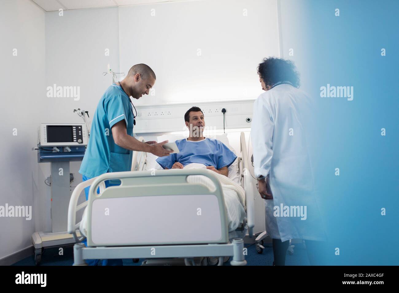 Medici con tablet digitali che fanno giri, parlando con il paziente nella stanza dell'ospedale Foto Stock