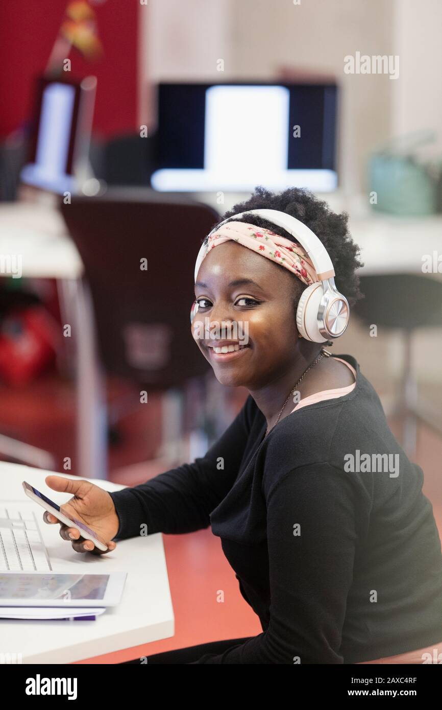 Studente femminile con orientamento verticale e sicuro con cuffie e smartphone Foto Stock