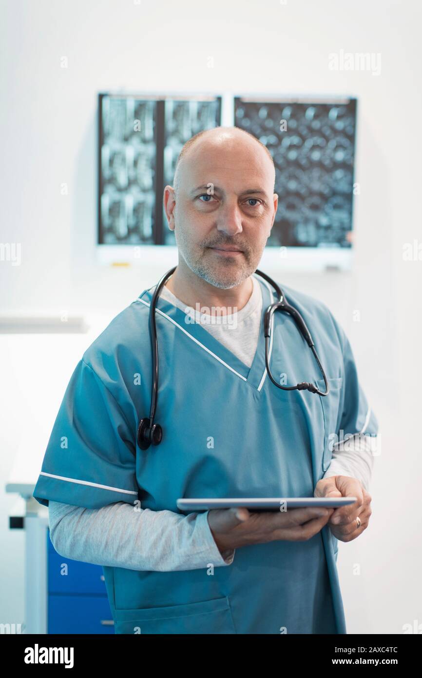 Medico maschile con ritratto sicuro che usa un tablet digitale in ospedale Foto Stock