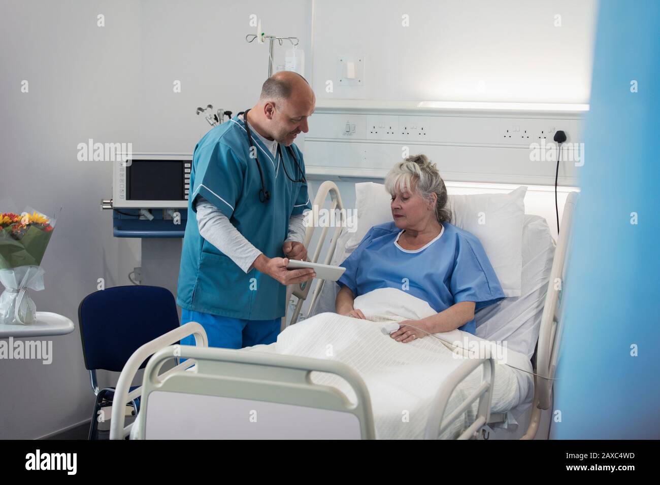 Dottore con tablet digitali che fa giri, parlando con i pazienti anziani nella stanza dell'ospedale Foto Stock
