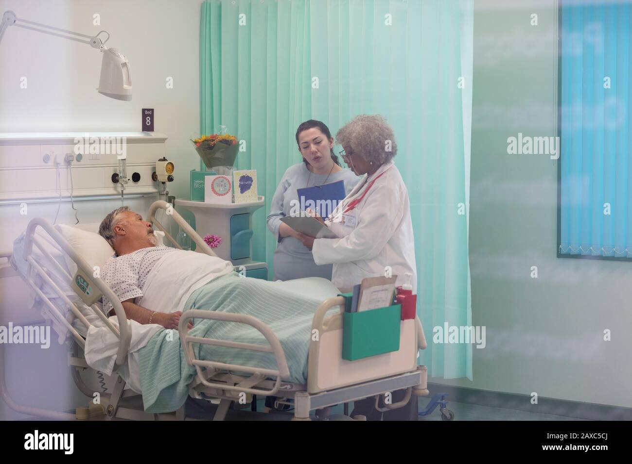 I medici facendo turni, parlando con il paziente nella stanza di ospedale Foto Stock