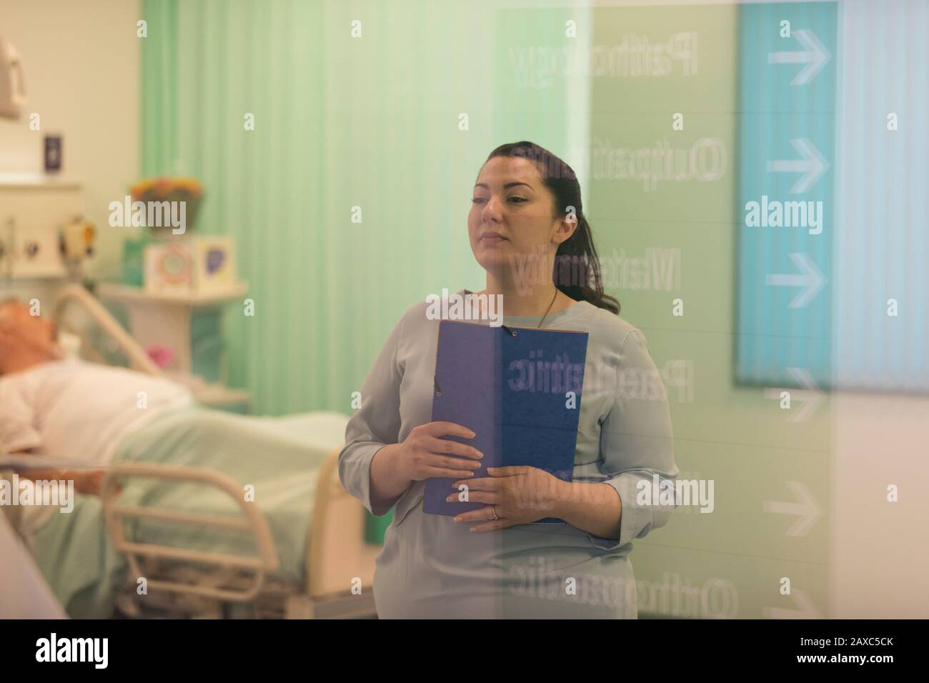 Medico femminile con cartella medica che fa i giri nel reparto dell'ospedale Foto Stock