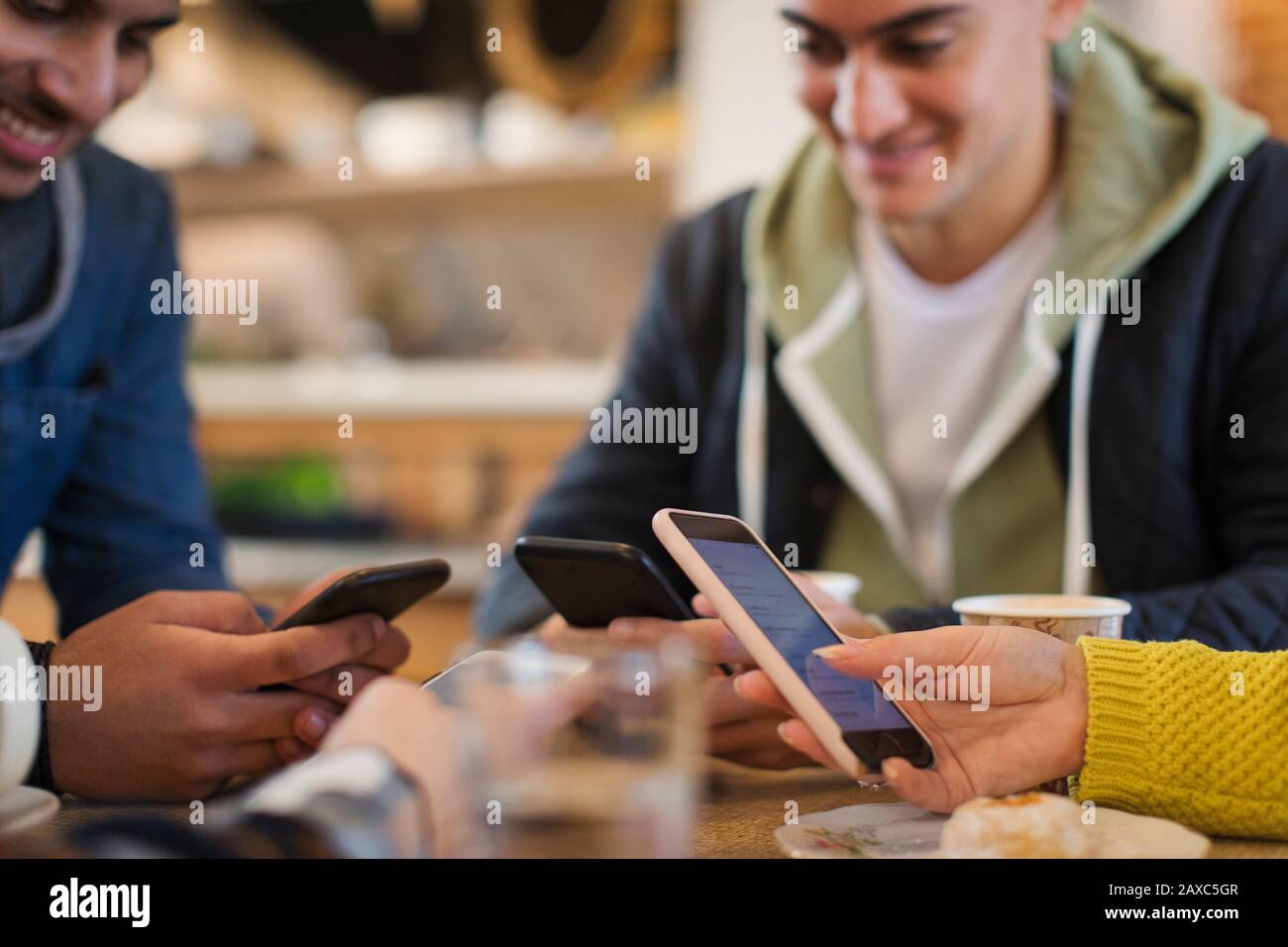 Giovani amici adulti che usano gli smartphone al tavolo del caffè Foto Stock