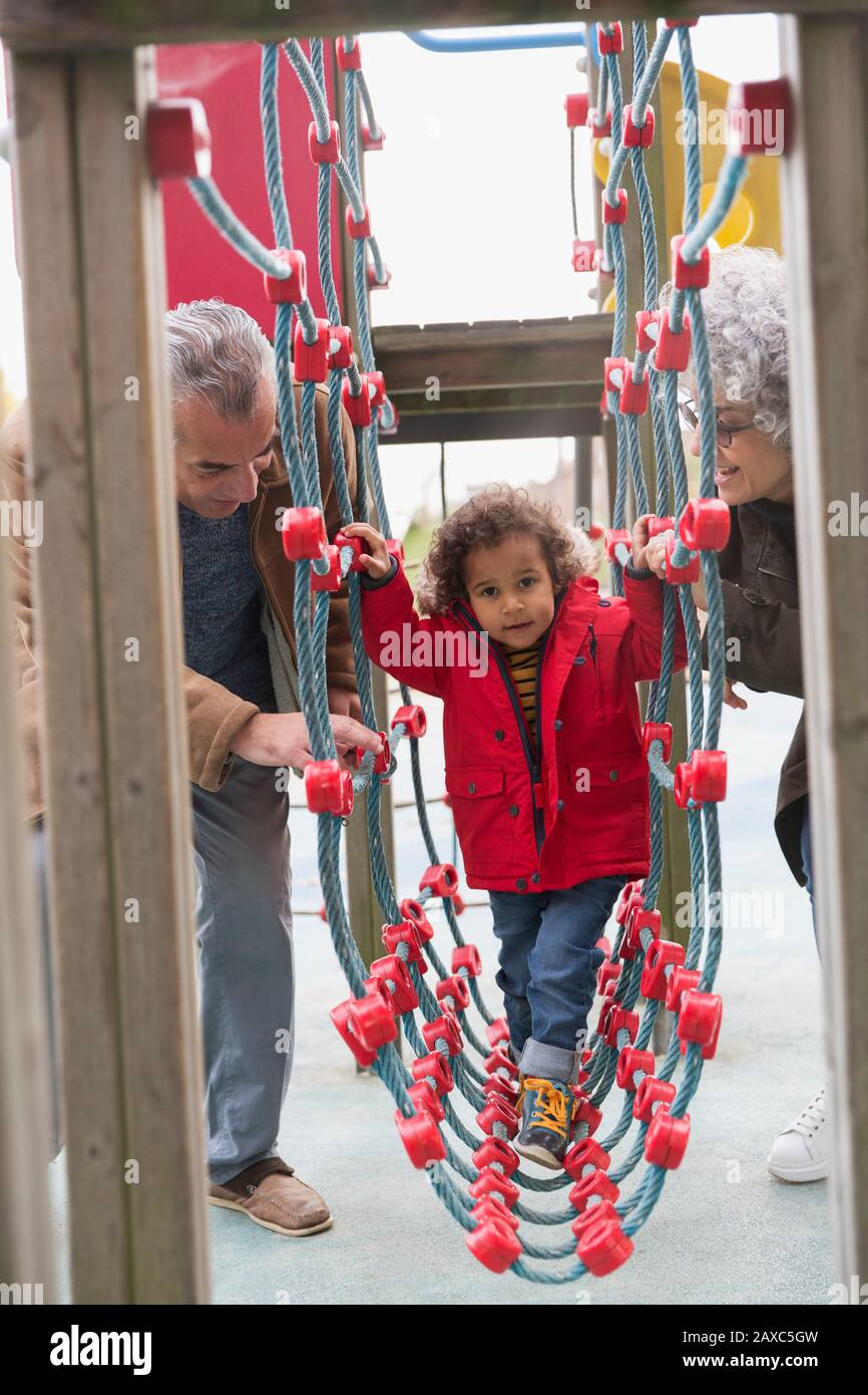 Nonni che giocano con il nipote nel parco giochi Foto Stock