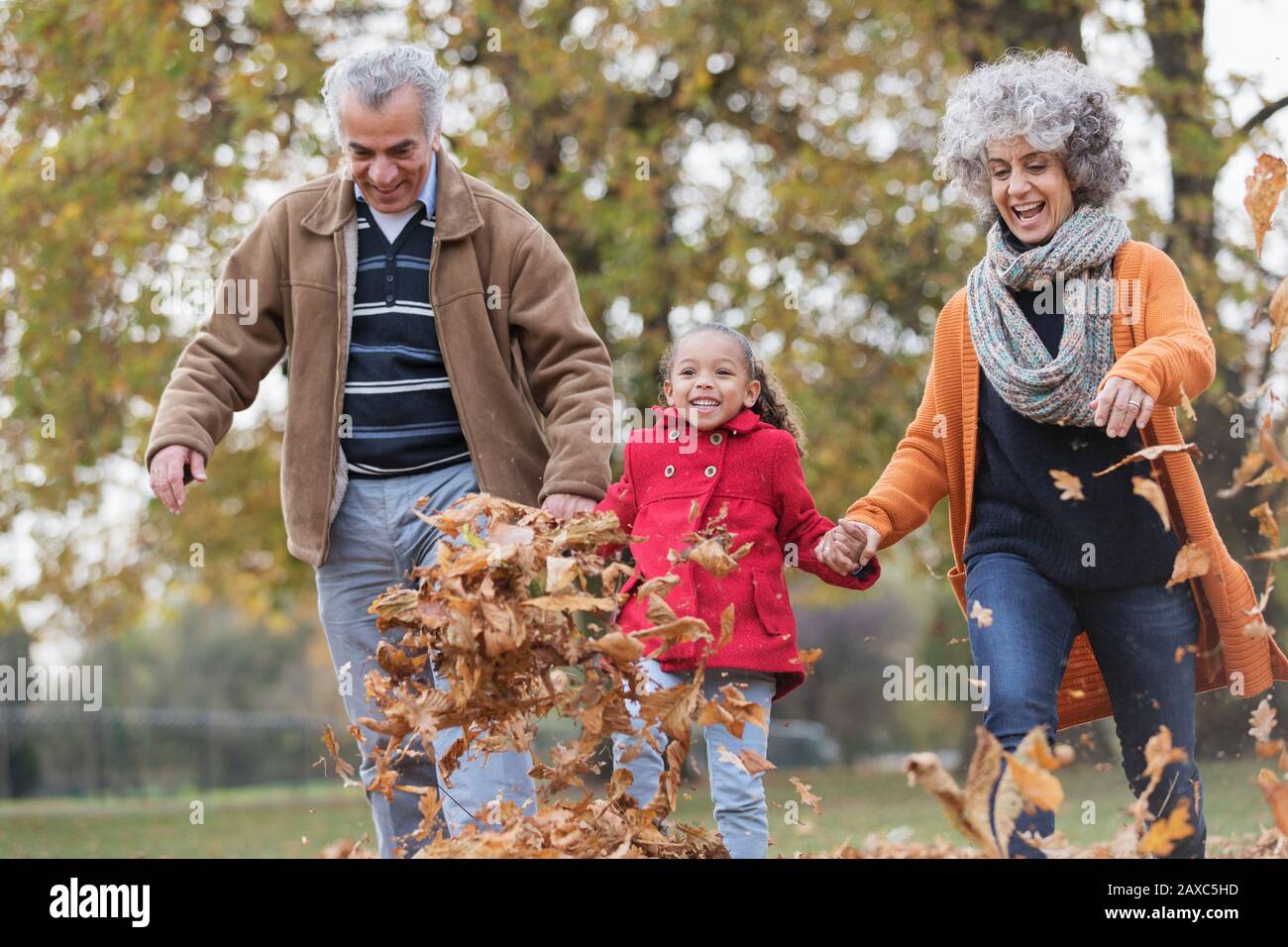 Nonni e nipoti giocosi che lasciano l'autunno nel parco Foto Stock