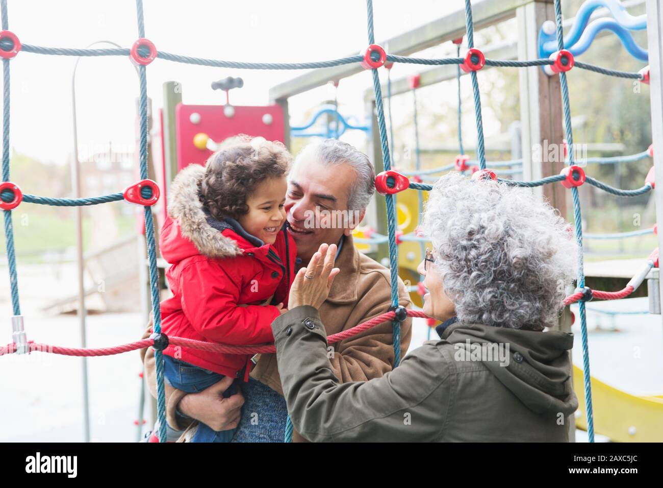 Nonni che giocano con il nipote nel parco giochi Foto Stock