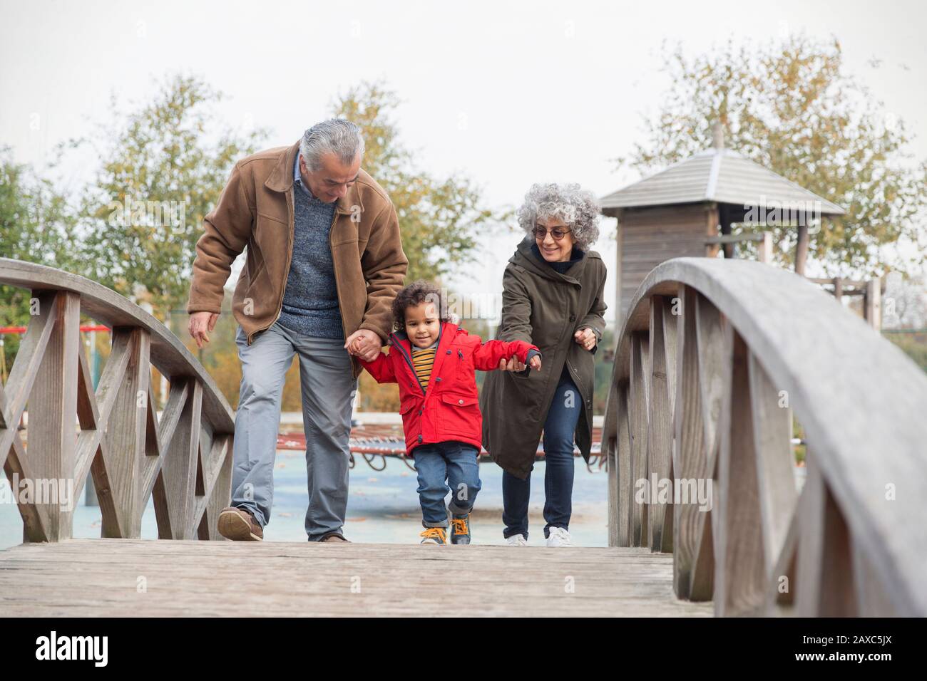 Nonni che camminano con il nipote sul ponte pedonale Foto Stock