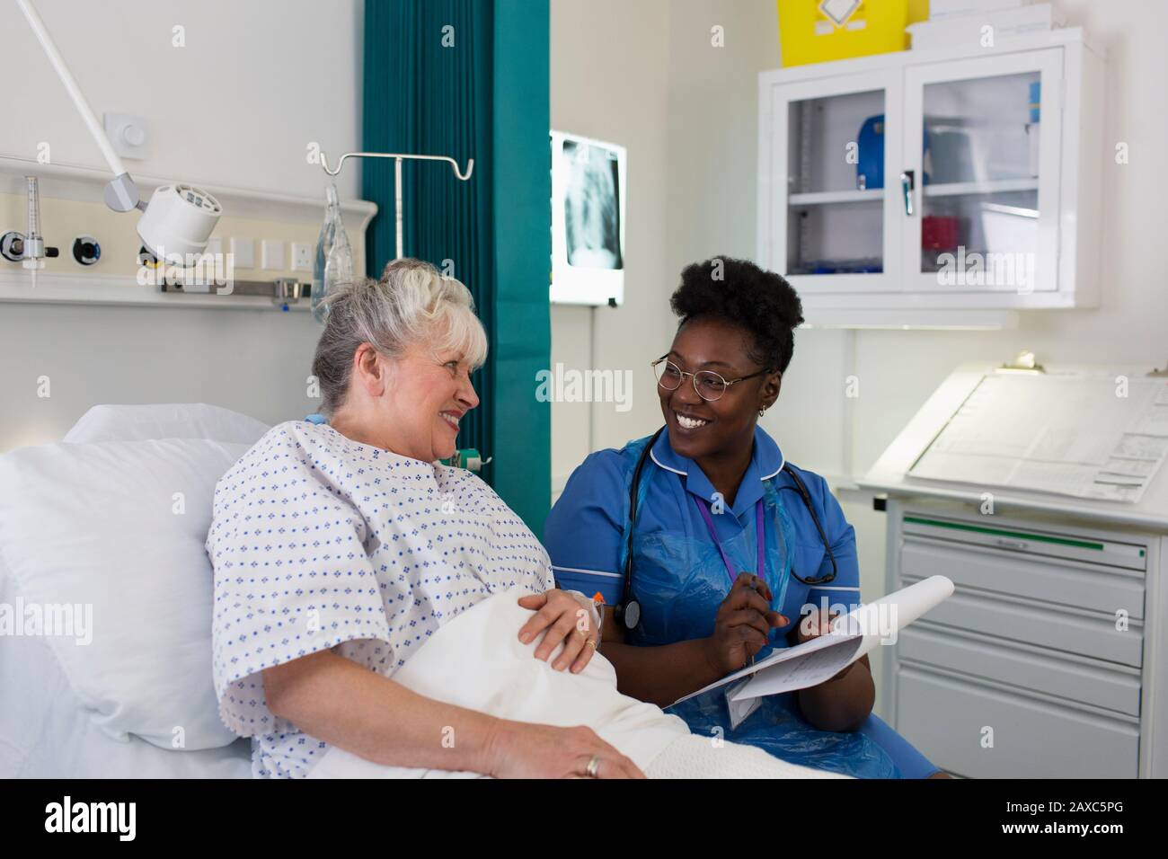 Infermiera femminile che parla con il paziente anziano nella stanza dell'ospedale Foto Stock