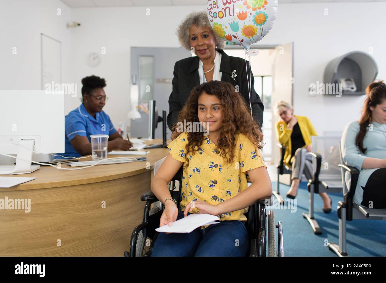 Donna che spinge la ragazza in sedia a rotelle in clinica Foto Stock