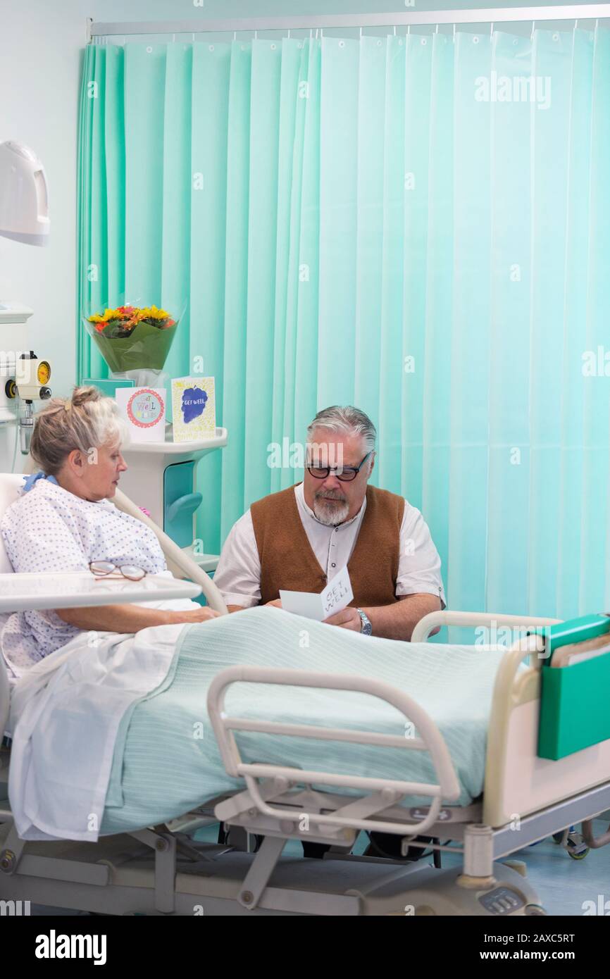 Uomo anziano con biglietto d'auguri per la visita della moglie che riposa nella stanza dell'ospedale Foto Stock