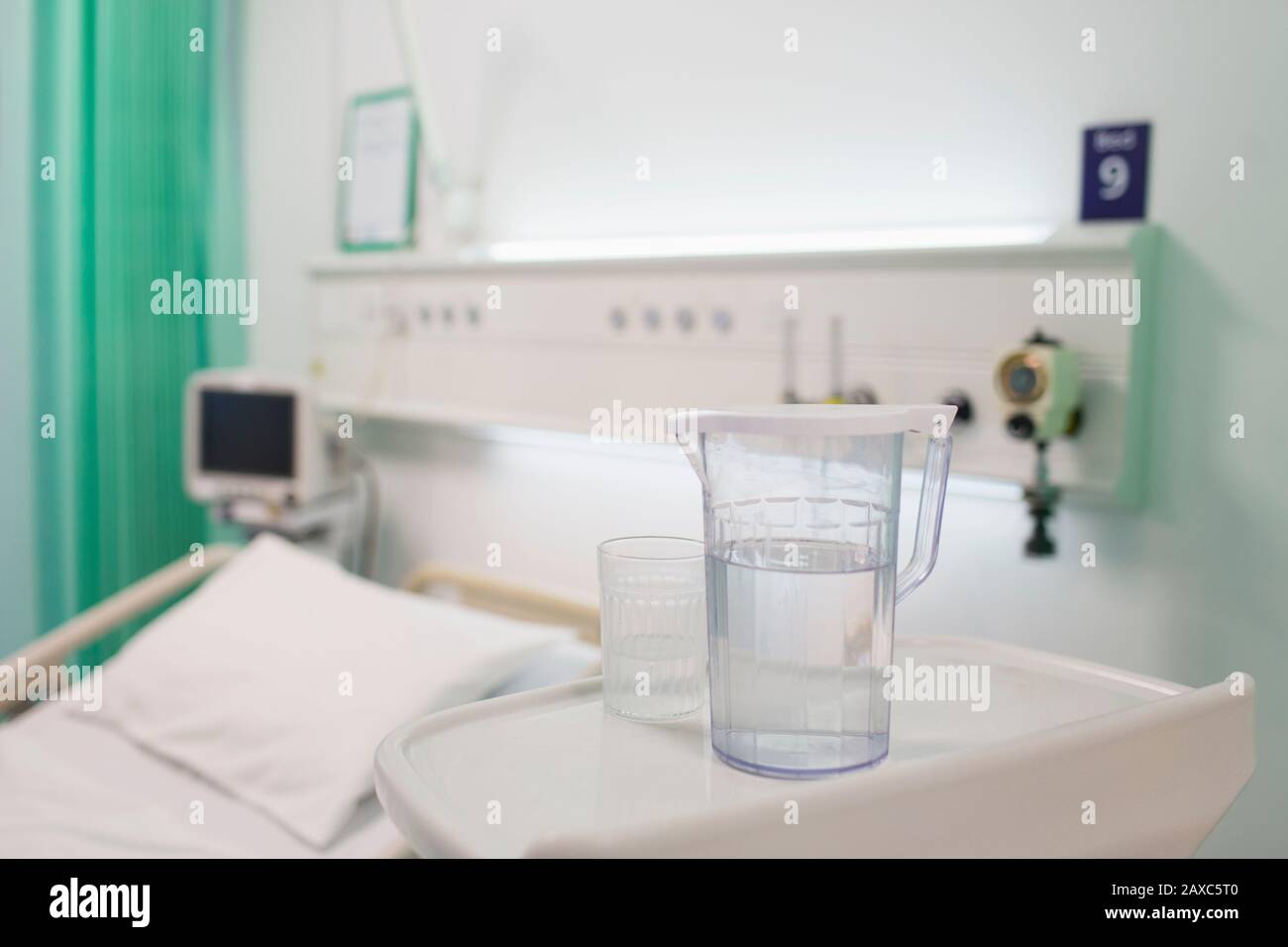 Caraffa d'acqua e bicchiere sul vassoio in una sala ospedaliera vuota Foto Stock