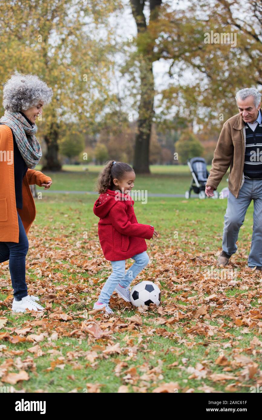 Nonni che giocano a calcio con la nipote nel parco autunnale Foto Stock