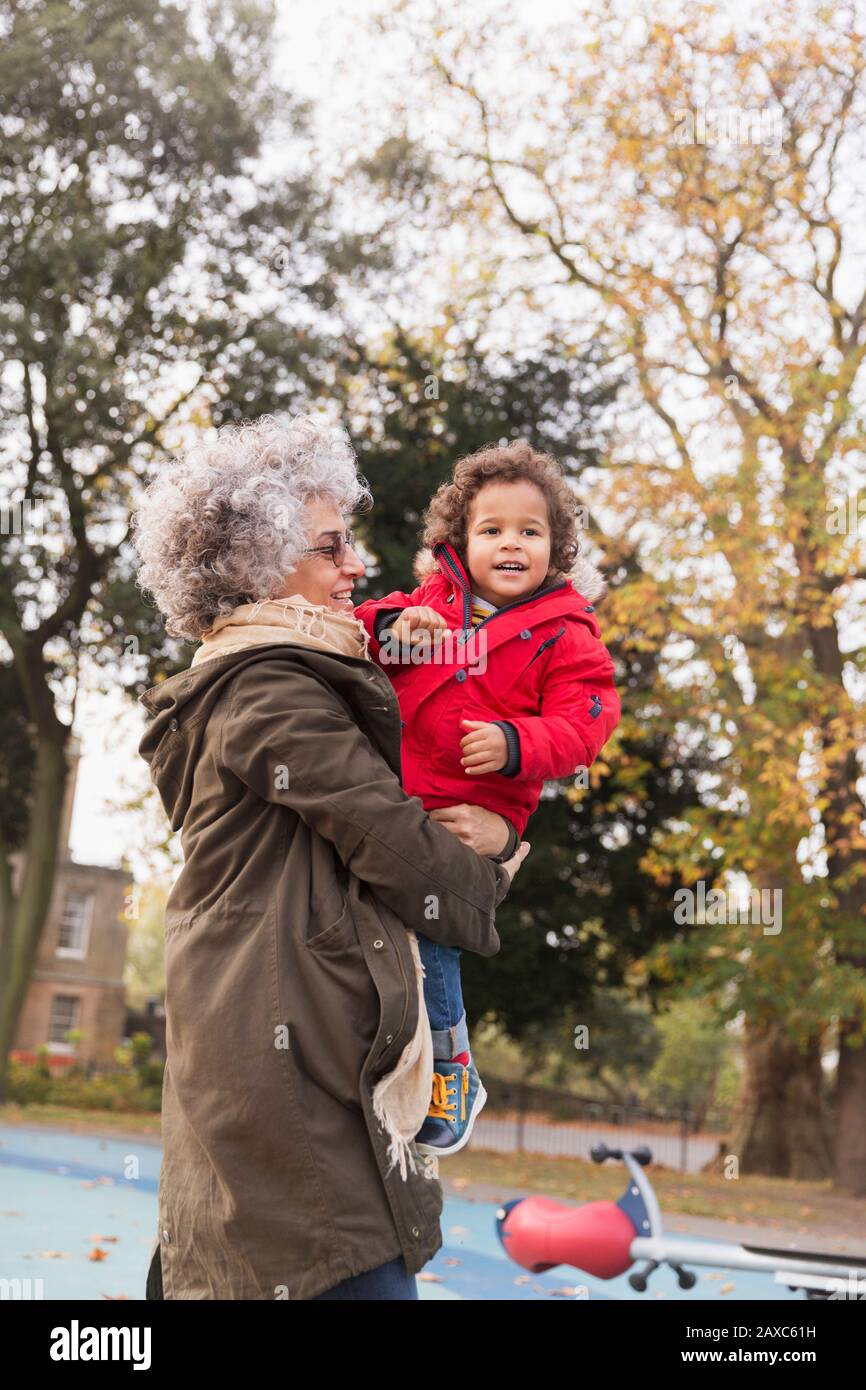 Nonna che porta nipote al parco giochi d'autunno Foto Stock