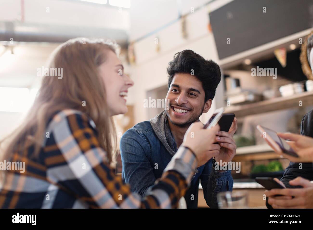 Felici i giovani amici adulti che usano gli smartphone nel caffè Foto Stock