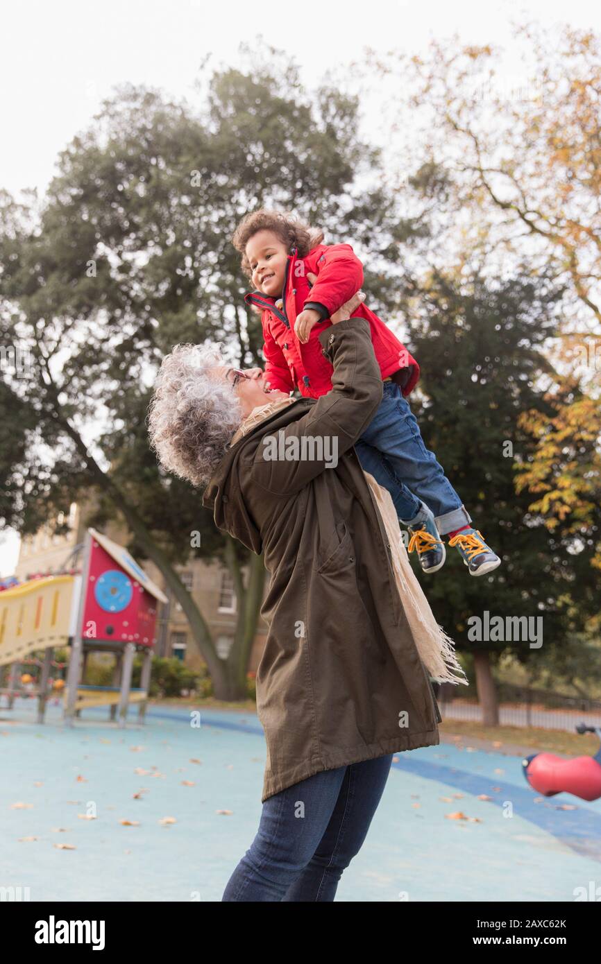 Nonna sollevamento nipote al parco giochi Foto Stock