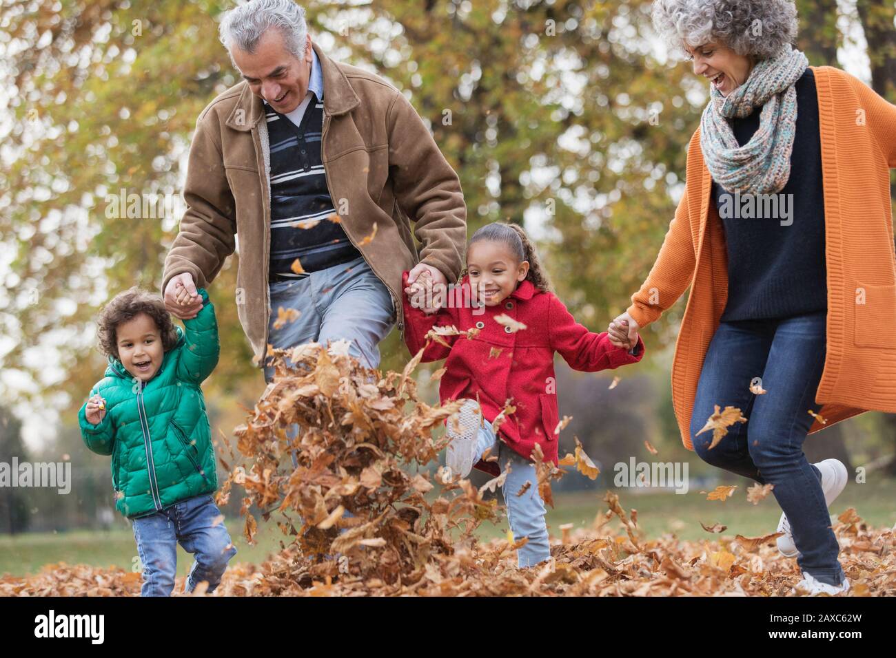 Nonni e nipoti giocosi che lasciano l'autunno nel parco Foto Stock