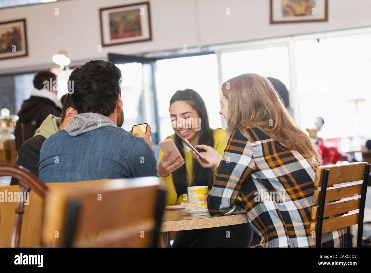 Giovani amici adulti che usano gli smartphone nel caffè Foto Stock