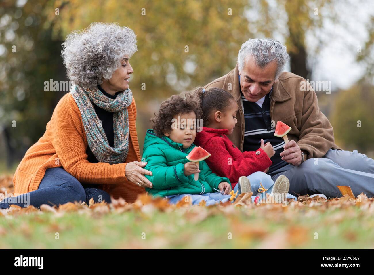 Nonni e nipoti che mangiano cocomero nel parco autunnale Foto Stock