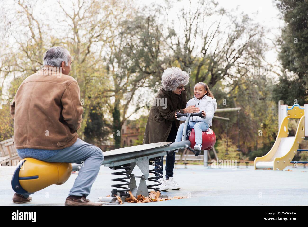 Nonni che giocano con la nipote sul mare al parco giochi Foto Stock