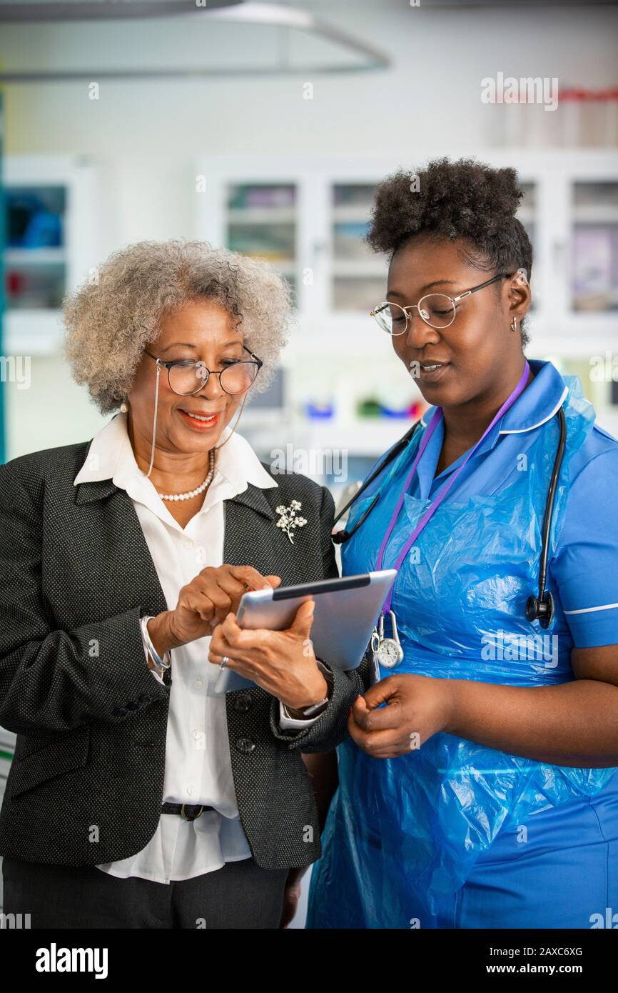 Medico e infermiere di sesso femminile che usa una compressa digitale in clinica Foto Stock