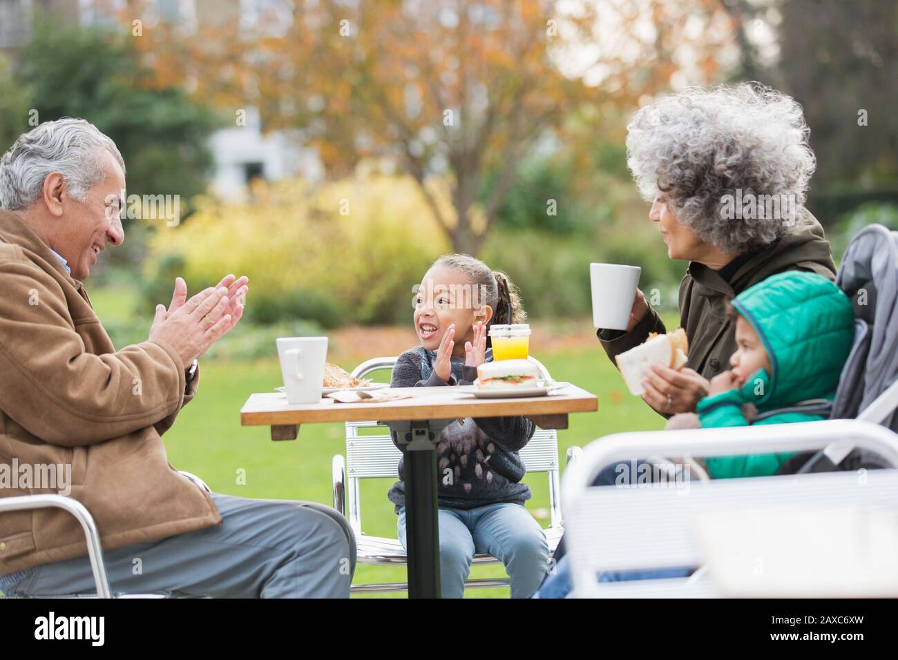 Nonni e nipoti che gustano il pranzo al tavolo del parco Foto Stock