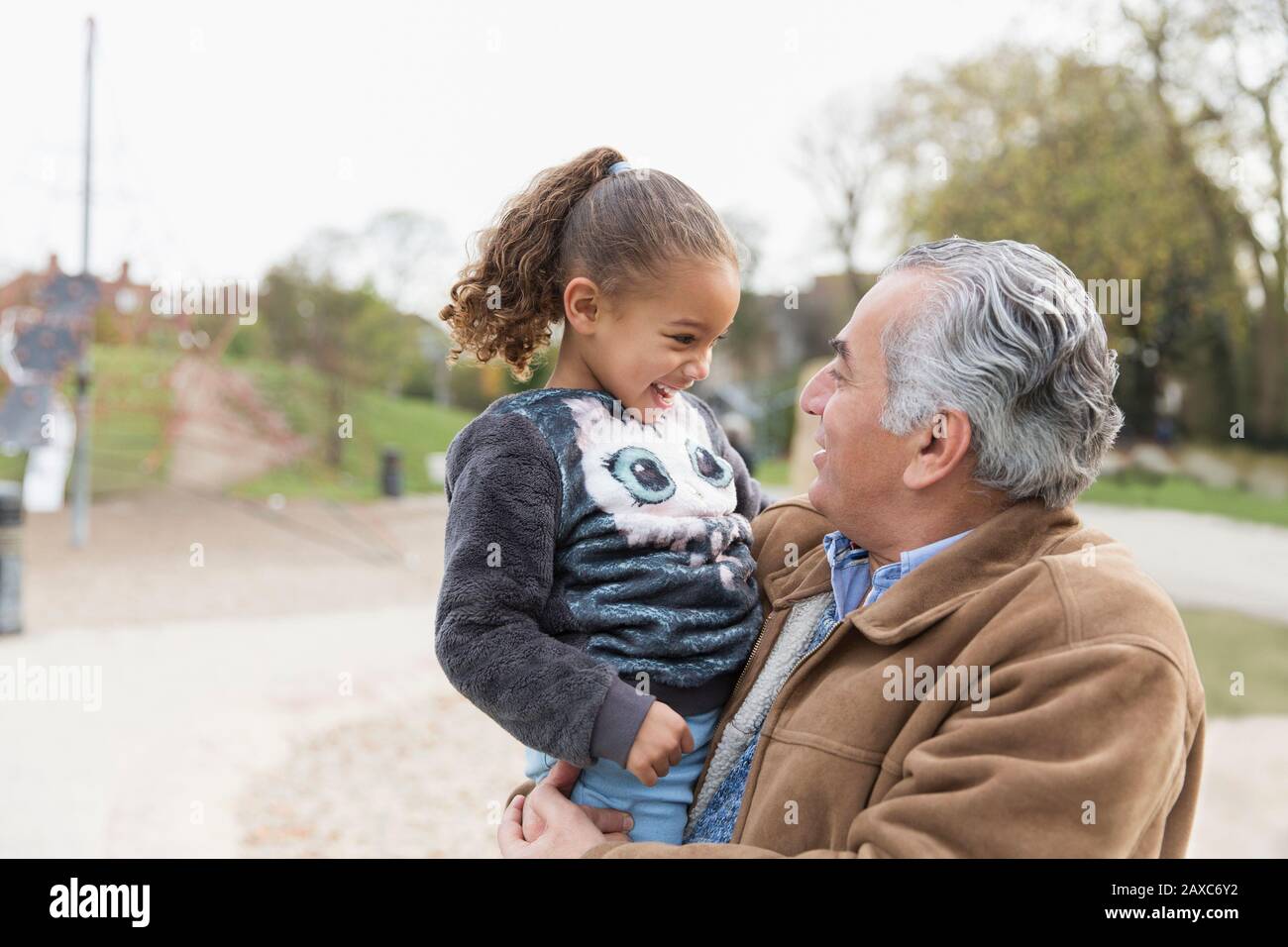 Nonno sorridente che tiene la nipote al parco Foto Stock